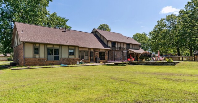 22547 S Dogwood Ct, Claremore, OK 74019 - rear view of house featuring brick siding, a yard, a shingled roof, a trampoline, and stucco siding