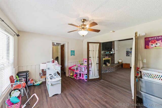 22547 S Dogwood Ct, Claremore, OK 74019 - game room featuring wood finished floors, a wainscoted wall, a textured ceiling, ceiling fan, and a fireplace