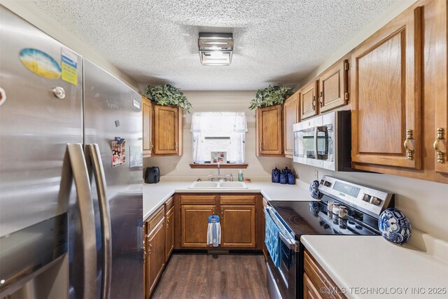 22547 S Dogwood Ct, Claremore, OK 74019 - kitchen featuring stainless steel appliances, brown cabinetry, dark wood-type flooring, light countertops, and a textured ceiling