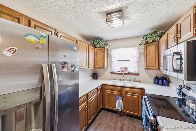 22547 S Dogwood Ct, Claremore, OK 74019 - kitchen featuring stainless steel appliances, brown cabinetry, a textured ceiling, dark wood-type flooring, and light countertops