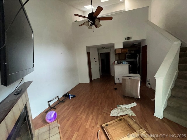 6737 S Peoria Ave Unit C205, Tulsa, OK 74136 - unfurnished living room featuring wood finished floors, stairs, a ceiling fan, a high ceiling, and a fireplace