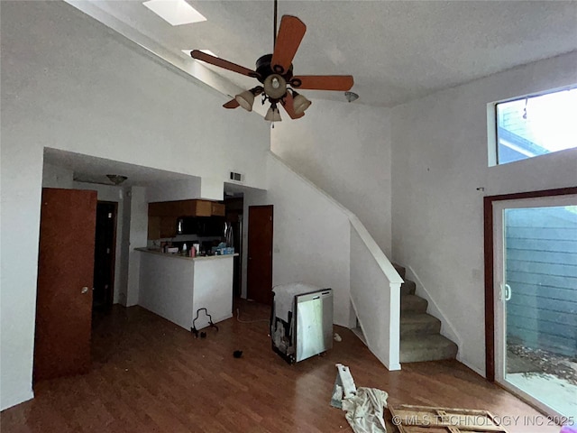 6737 S Peoria Ave Unit C205, Tulsa, OK 74136 - unfurnished living room featuring wood finished floors, high vaulted ceiling, a ceiling fan, and stairway
