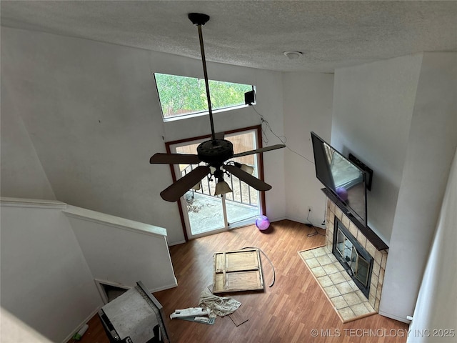 6737 S Peoria Ave Unit C205, Tulsa, OK 74136 - unfurnished living room featuring wood finished floors, a textured ceiling, ceiling fan, and a fireplace
