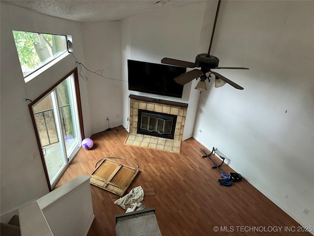 6737 S Peoria Ave Unit C205, Tulsa, OK 74136 - unfurnished living room featuring a tiled fireplace, a ceiling fan, wood finished floors, and a textured ceiling