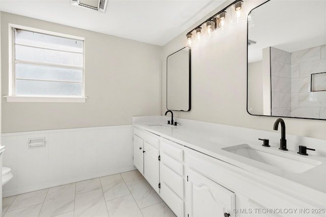 6722 S 72nd E Ave, Tulsa, OK 74133 - bathroom featuring marble look tile flooring, double vanity, a wainscoted wall, and toilet