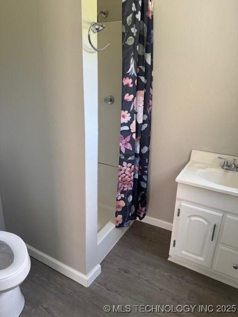 904 W Tishomingo, Madill, OK 73446 - full bathroom featuring wood finished floors, toilet, a shower with curtain, and vanity
