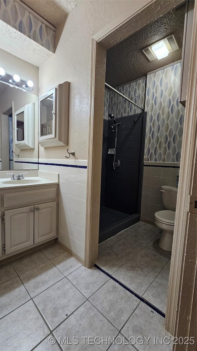 6401 S 86th E Ave, Tulsa, OK 74133 - bathroom featuring tile walls, a stall shower, a textured ceiling, vanity, and tile patterned flooring