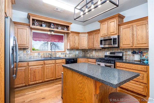 3127 Pleasant Hill Rd, Caddo, OK 74729 - kitchen with stainless steel appliances, a sink, light wood-style floors, dark countertops, and a kitchen island