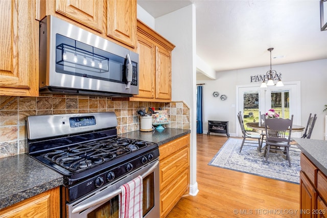 3127 Pleasant Hill Rd, Caddo, OK 74729 - kitchen featuring appliances with stainless steel finishes, light wood finished floors, dark countertops, tasteful backsplash, and pendant lighting
