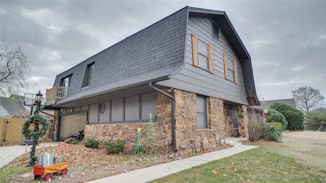 8722 E 74th Pl, Tulsa, OK 74133 - view of front of house featuring a balcony, a shingled roof, an attached garage, and stone siding