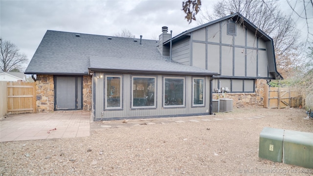 8722 E 74th Pl, Tulsa, OK 74133 - rear view of property featuring stone siding, a chimney, a patio area, and a shingled roof