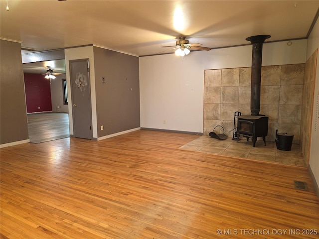 14202 E 492nd Rd, Claremore, OK 74019 - unfurnished living room with a ceiling fan, a wood stove, wood finished floors, and ornamental molding