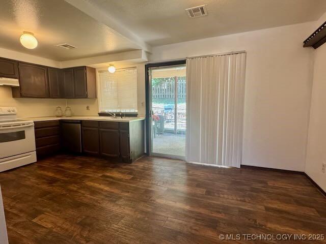 1822 N Xenophon Ave, Tulsa, OK 74127 - kitchen with white electric stove, under cabinet range hood, light countertops, dark wood-style floors, and dark brown cabinets