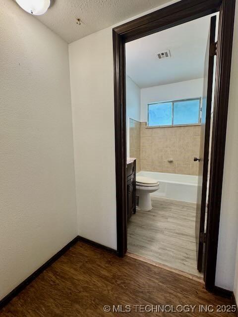 1822 N Xenophon Ave, Tulsa, OK 74127 - bathroom with wood finished floors, vanity, a bathtub, and a textured ceiling