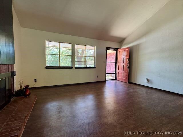 1822 N Xenophon Ave, Tulsa, OK 74127 - unfurnished living room with dark wood-style floors, vaulted ceiling, and a brick fireplace