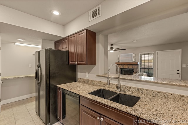 6376 S 80th E Ave Unit 41H, Tulsa, OK 74133 - kitchen with black appliances, a ceiling fan, a stone fireplace, light stone counters, and light tile patterned floors