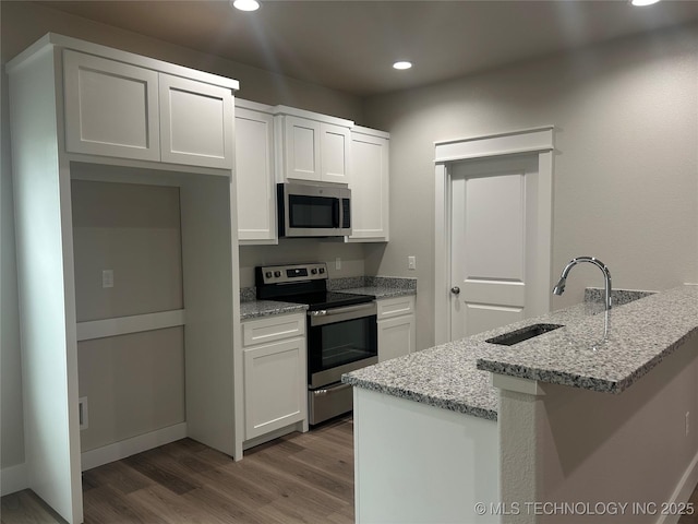 373 Worth Ave, Durant, OK 74701 - kitchen featuring stainless steel appliances, recessed lighting, wood finished floors, white cabinets, and a peninsula