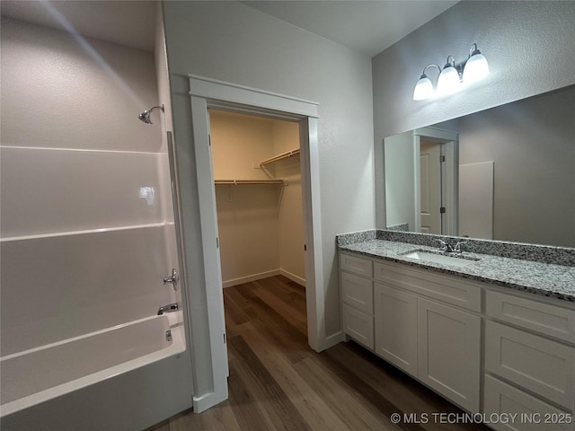 373 Worth Ave, Durant, OK 74701 - bathroom featuring wood finished floors, vanity, washtub / shower combination, and a walk in closet