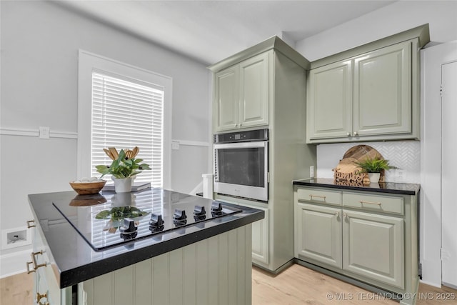 408 K SW, Ardmore, OK 73401 - kitchen featuring oven, dark countertops, decorative backsplash, light wood-style flooring, and black electric stovetop