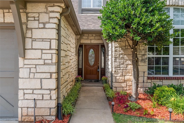 8811 E 110th St S, Bixby, OK 74133 - view of exterior entry featuring stone siding and a shingled roof