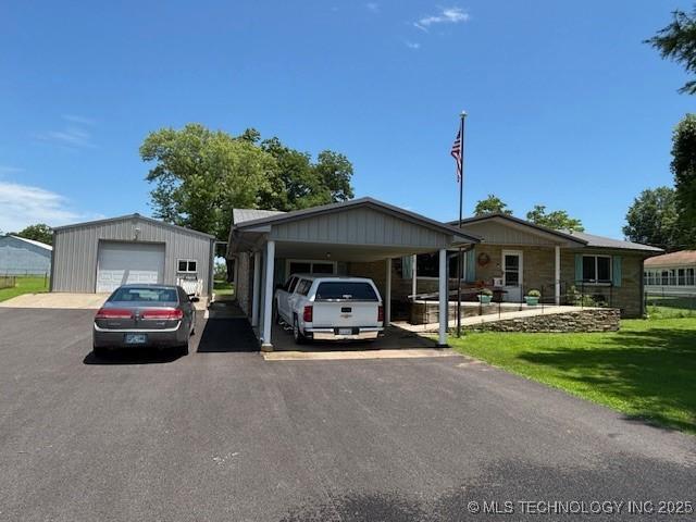 902 NE Rushwood Dr, Stigler, OK 74462 - view of front of house featuring a detached garage, driveway, a carport, a front lawn, and an outdoor structure