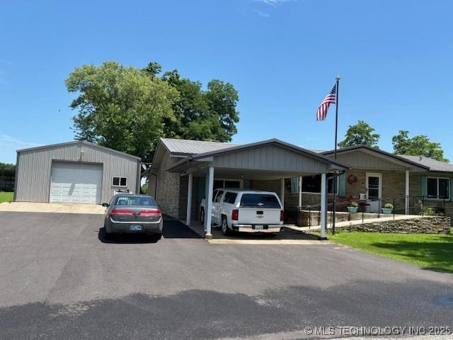 902 NE Rushwood Dr, Stigler, OK 74462 - single story home with a garage, a carport, an outdoor structure, and stone siding