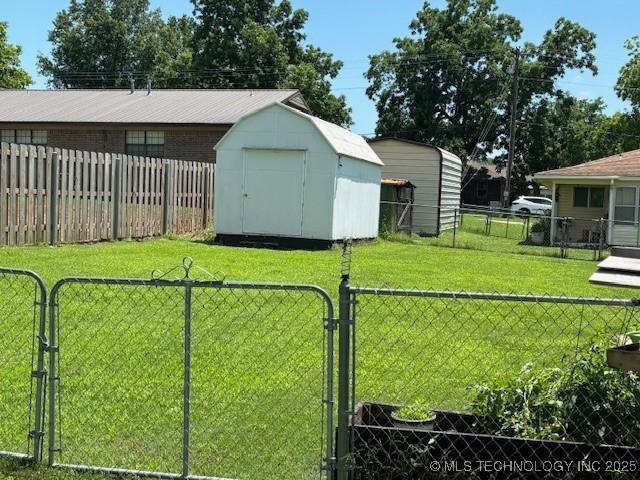 902 NE Rushwood Dr, Stigler, OK 74462 - fenced backyard featuring a storage unit and a gate