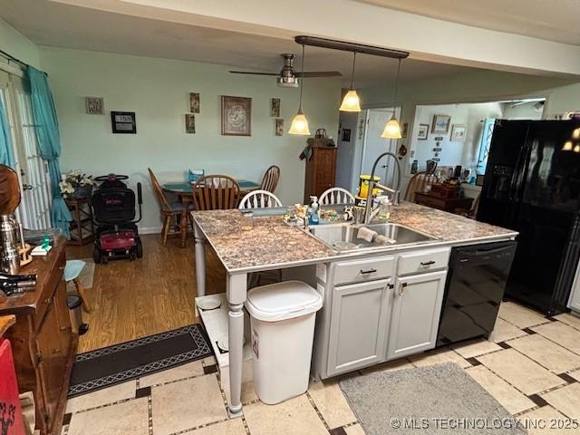 902 NE Rushwood Dr, Stigler, OK 74462 - kitchen featuring black appliances, a kitchen island with sink, pendant lighting, and light countertops