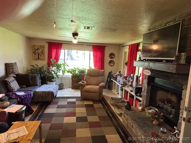 902 NE Rushwood Dr, Stigler, OK 74462 - living room featuring ceiling fan, a fireplace, a textured ceiling, and tile patterned floors