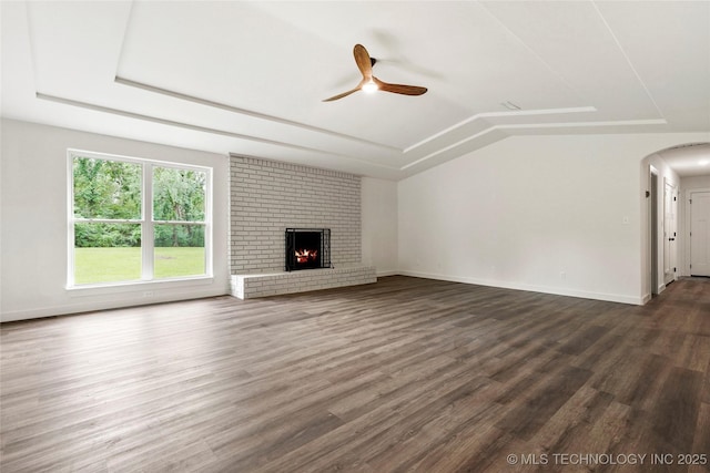 10062 E Northshire St, Claremore, OK 74017 - unfurnished living room with ceiling fan, dark wood-type flooring, arched walkways, a brick fireplace, and vaulted ceiling