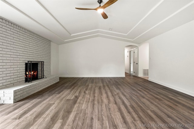 10062 E Northshire St, Claremore, OK 74017 - unfurnished living room with a ceiling fan, a brick fireplace, arched walkways, wood finished floors, and vaulted ceiling