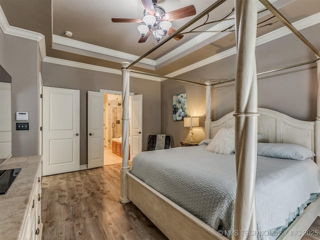 9025 N 100th E Ave, Owasso, OK 74055 - bedroom with a tray ceiling, ornamental molding, wood finished floors, connected bathroom, and a ceiling fan