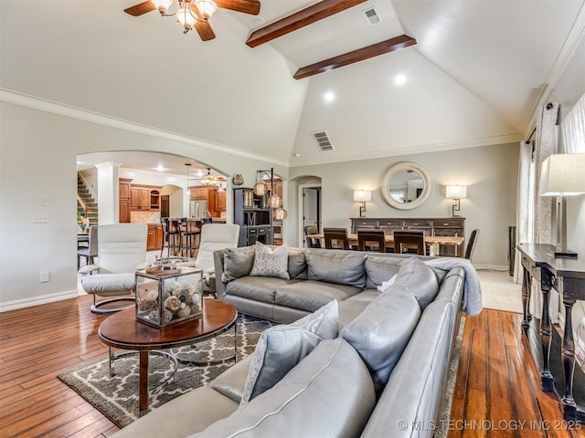 9025 N 100th E Ave, Owasso, OK 74055 - living area with arched walkways, ceiling fan, light wood finished floors, decorative columns, and high vaulted ceiling