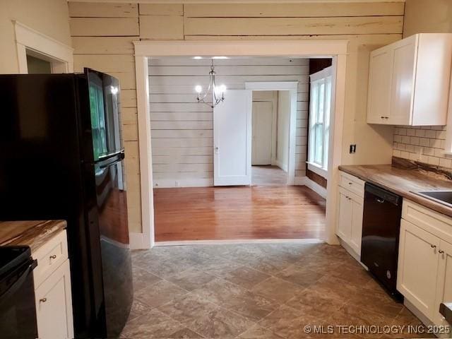 1319 Bixby St, Ardmore, OK 73401 - kitchen with black appliances, wooden walls, white cabinetry, a chandelier, and decorative backsplash