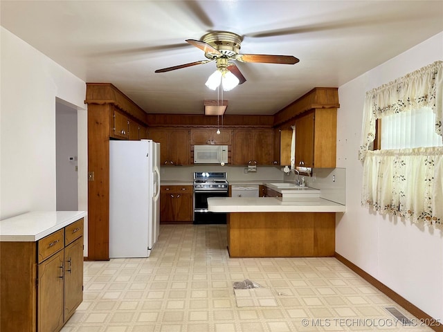 705 W 3rd St, Skiatook, OK 74070 - kitchen featuring white appliances, a peninsula, light countertops, and brown cabinetry
