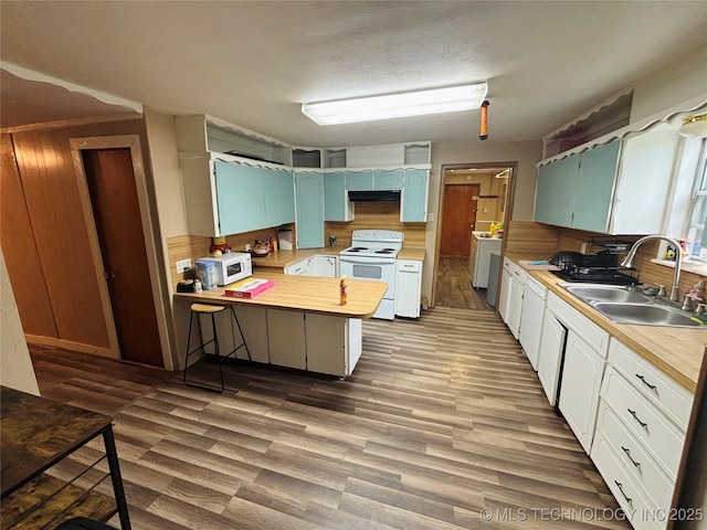 1503 Hillcrest, Durant, OK 74701 - kitchen with white appliances, a peninsula, light countertops, wood finished floors, and under cabinet range hood