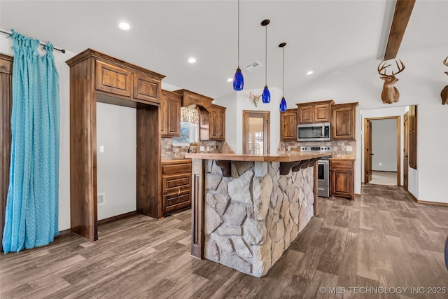 6335 S Watson, Sulphur, OK 73086 - kitchen with stainless steel appliances, dark wood-style flooring, tasteful backsplash, brown cabinetry, and decorative light fixtures