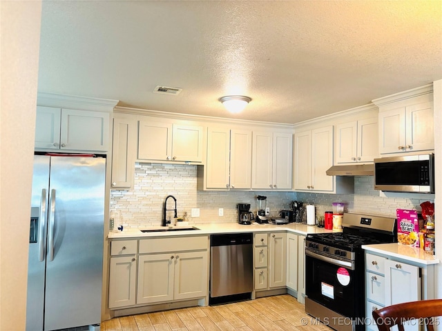 7936 S 72nd E Ave, Tulsa, OK 74133 - kitchen featuring appliances with stainless steel finishes, under cabinet range hood, light countertops, light wood finished floors, and decorative backsplash