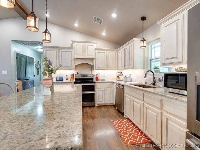 23997 County Road 1475th Loop, Ada, OK 74820 - kitchen with stainless steel appliances, vaulted ceiling, dark wood-type flooring, backsplash, and light stone counters