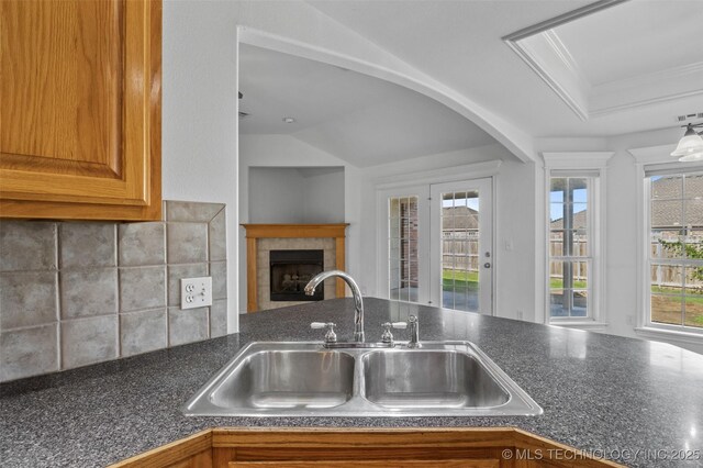 13124 N 133rd E Ave, Collinsville, OK 74021 - kitchen with dark countertops, a tile fireplace, tasteful backsplash, and brown cabinetry