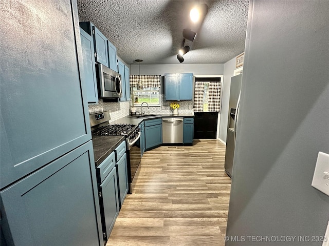 3617 S 74th W Ct, Tulsa, OK 74107 - kitchen featuring appliances with stainless steel finishes, dark countertops, backsplash, light wood finished floors, and blue cabinets