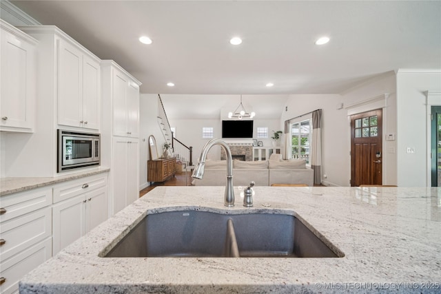 1617 S St Louis Ave, Tulsa, OK 74120 - kitchen featuring stainless steel microwave, open floor plan, white cabinets, recessed lighting, and light stone countertops