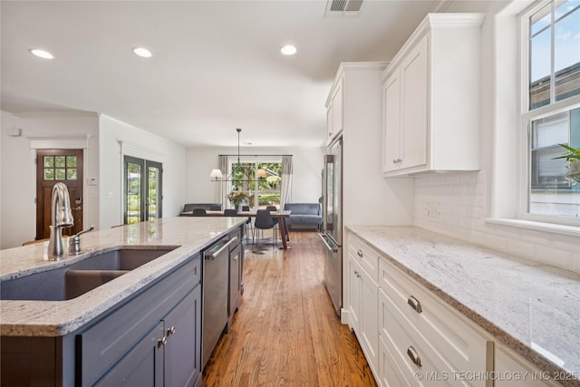 1617 S St Louis Ave, Tulsa, OK 74120 - kitchen with appliances with stainless steel finishes, white cabinets, light wood-style flooring, recessed lighting, and decorative backsplash