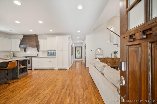 1617 S St Louis Ave, Tulsa, OK 74120 - kitchen with custom range hood, appliances with stainless steel finishes, light countertops, open floor plan, and white cabinetry