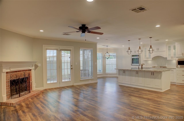 5512 S Columbia Ct, Tulsa, OK 74105 - unfurnished living room featuring a brick fireplace, ceiling fan, wood finished floors, recessed lighting, and healthy amount of natural light