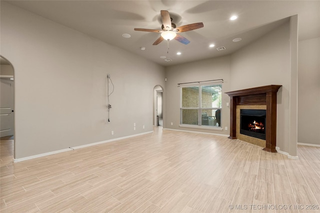 1908 E 133rd Ct, Bixby, OK 74008 - unfurnished living room featuring arched walkways, ceiling fan, a tile fireplace, light wood-type flooring, and recessed lighting