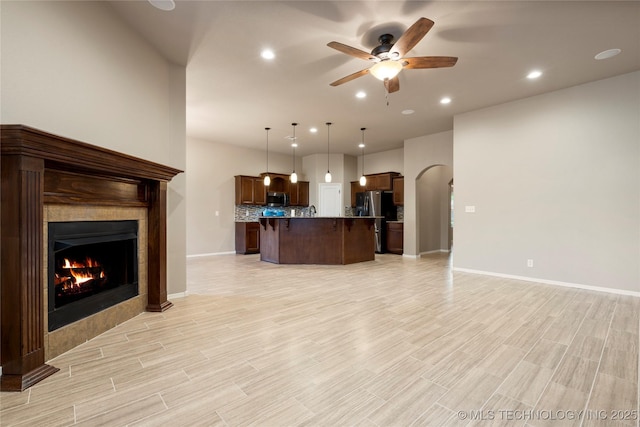 1908 E 133rd Ct, Bixby, OK 74008 - unfurnished living room featuring ceiling fan, a tile fireplace, recessed lighting, light wood-style flooring, and arched walkways