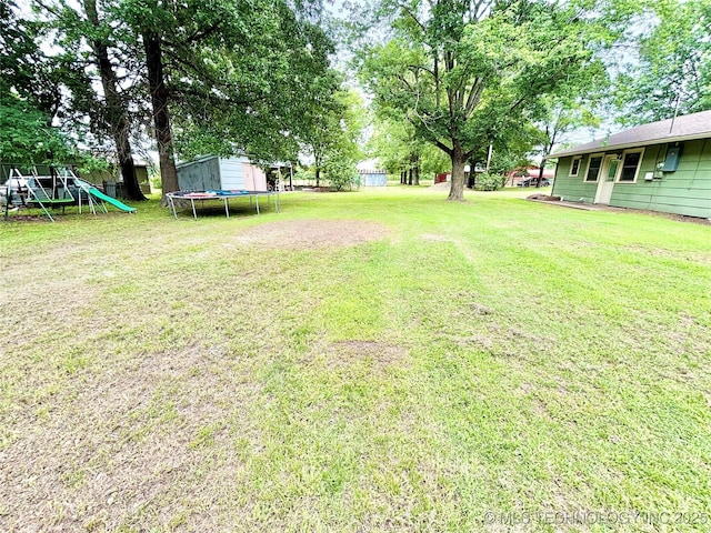 106 E Elk Rd, Whitefield, OK 74472 - view of green lawn with a trampoline, a playground, and a storage unit