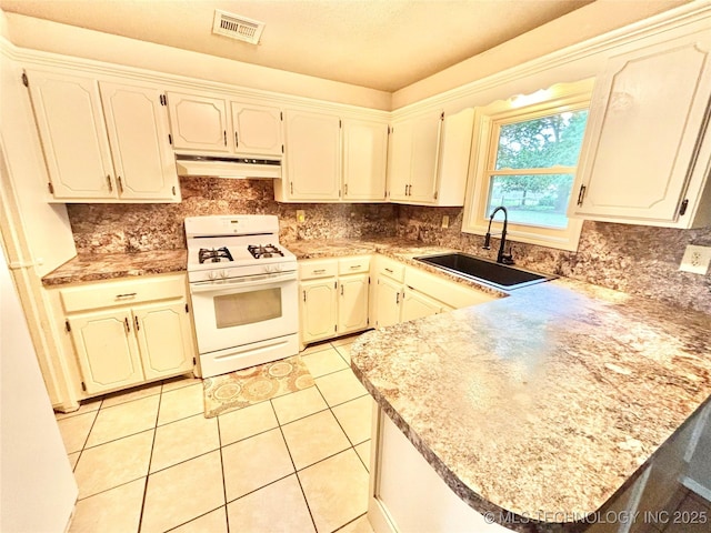 106 E Elk Rd, Whitefield, OK 74472 - kitchen featuring white range with gas cooktop, under cabinet range hood, a peninsula, and tasteful backsplash