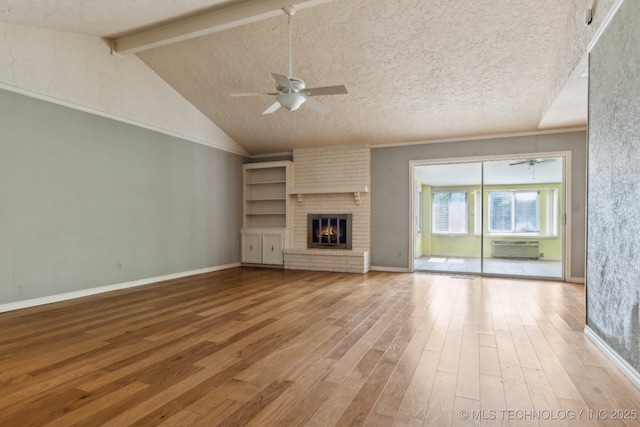 8202 S Ash Pl, Broken Arrow, OK 74011 - unfurnished living room with ceiling fan, wood finished floors, a wall mounted AC, a fireplace, and a textured ceiling
